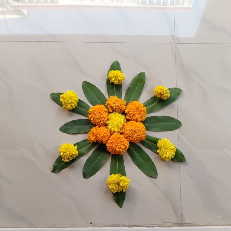 an arrangement of flowers is arranged on the floor with green leaves and yellow flowers in the center