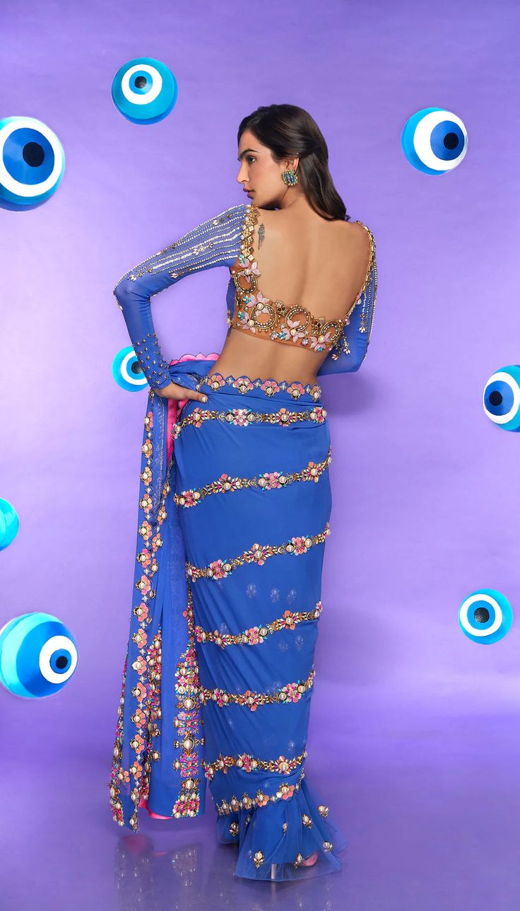 A classic studded pre-stitched blue saree in georgette and tulle bottom embellished with reflective acrylics, pearls, sequins, and glass cut crystals. Paired with a full sleeve blouse embellished in metal pieces, pearls, and crystals.From Papa Don't Preach's Nazar Na Lage collection. DELIVERY TIMEPlease allow 8-12 weeks for your outfit to arrive. FABRIC DETAILSGeorgette, Tulle Professional cleaning only. Traditional Blue Pre-draped Saree For Party, Party Wear Embellished Pre-draped Saree For Festivals, Festive Blue Pre-draped Saree For Evening, Embellished Long Sleeve Pre-draped Saree For Party, Bollywood Style Hand Embellished Pre-draped Saree For Festivals, Hand Embellished Blouse Piece For Reception And Festivals, Blue Zari Work Party Wear Pre-draped Saree, Hand Embellished Blouse Piece For Festivals And Receptions, Hand Embellished Blouse Piece For Receptions And Festivals