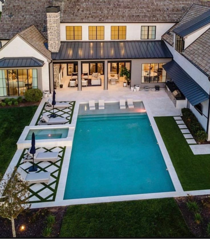 an aerial view of a house with a pool in the yard and patio furniture on the lawn