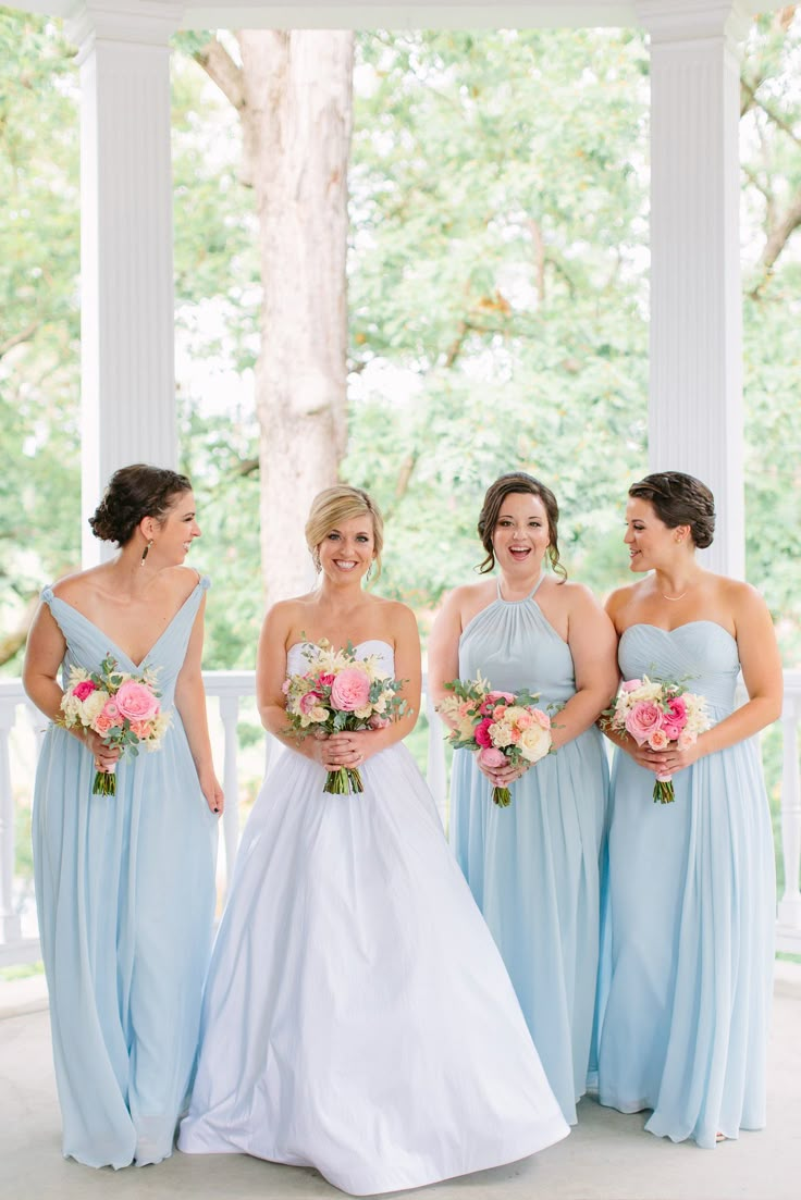 the bride and her bridesmaids are all dressed in light blue dresses with pink bouquets