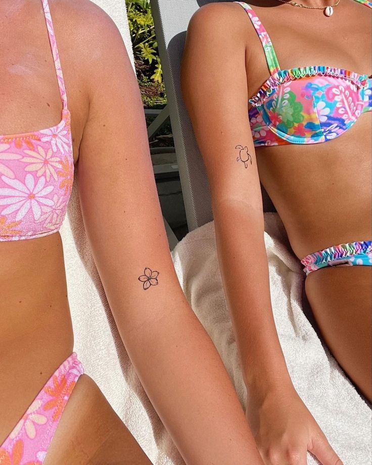 two women in bikinis with tattoos on their arms