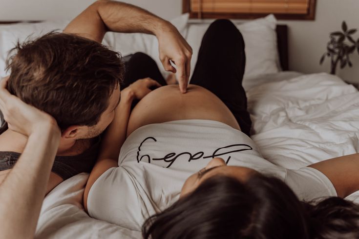 a man and woman laying on top of a bed next to each other with writing on their backs