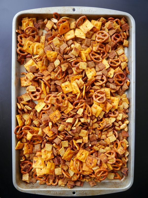 a baking dish filled with cheetos and pretzels on a black surface