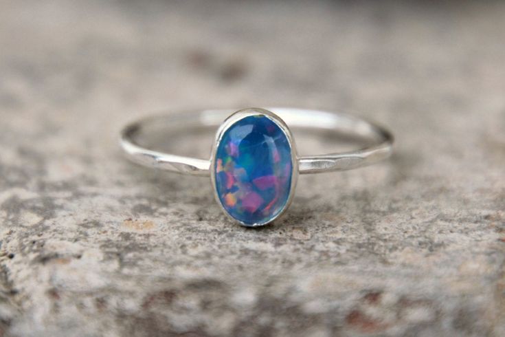 I am super excited to finally show off these new opals! I have been working with a wonderful supplier who specially made these gemstones just for my shop, so you will not find them anywhere else! This listing is for ONE light blue 8mm X 6mm oval opal ring! These crystal opals are more translucent with a nice amount of fire and sparkle! Each 1.3mm band is made using Argentium sterling silver. I hand forge each band, fuse them together, solder on the fine silver bezel cups, then put them in my tum Opal Gemstone Stackable Rings Gift, Opal Gemstone Stackable Gift Rings, Stackable Opal Promise Ring, Opal Birthstone Stackable Rings As Gift, Stackable Opal Birthstone Rings As Gift, Opal Stackable Rings With Birthstone For Promise, Stackable Opal Birthstone Ring For Promise, Stackable Opal Birthstone Promise Ring, Dainty Opal Gemstone Stackable Rings