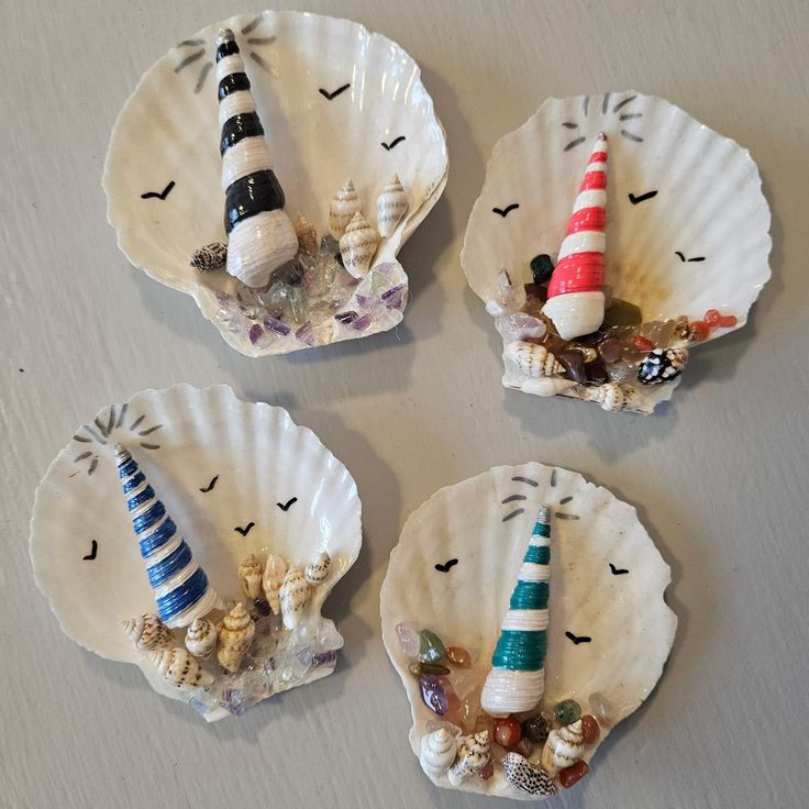 three small seashells with lighthouse decorations on them