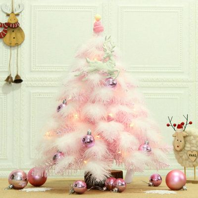 a pink christmas tree with ornaments around it