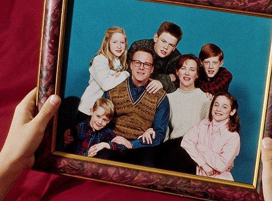 a family portrait is being held up in front of a blue background with the image of two adults and three children