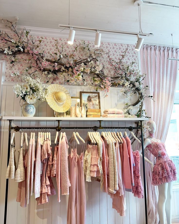 clothes are hanging on a rack in front of a window with pink and white flowers