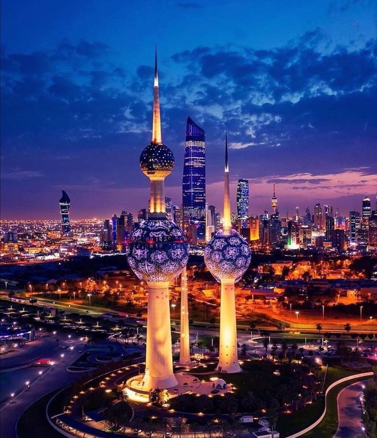 the city skyline is lit up at night with tall buildings in the foreground and two giant balls on top