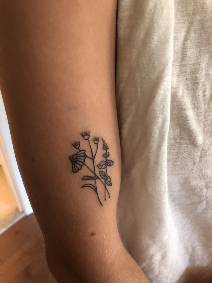 a small tattoo on the arm of a woman with flowers in it's center