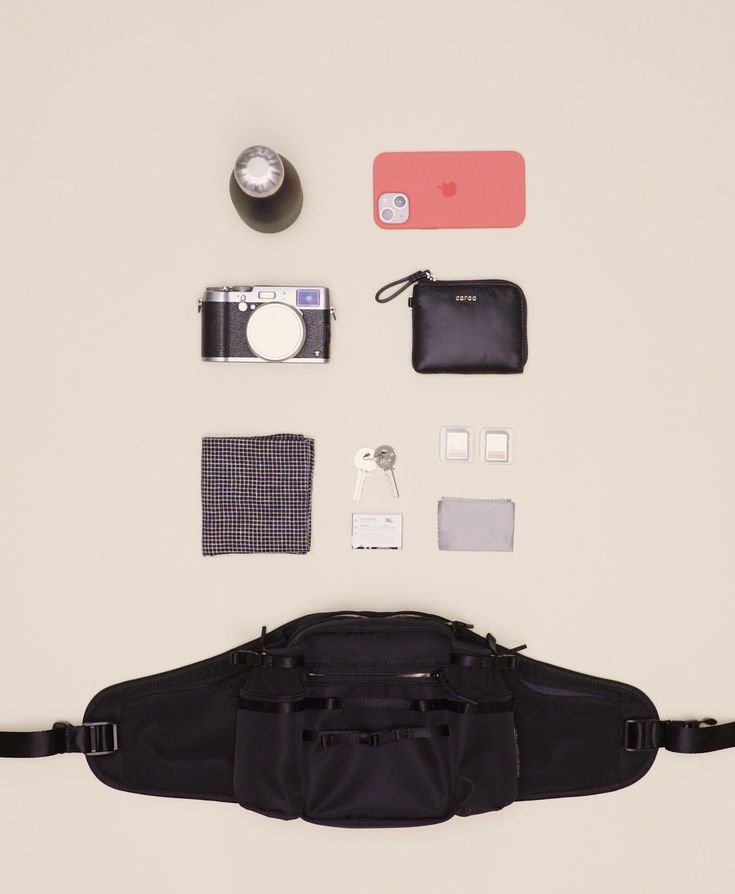 the contents of a camera bag laid out on top of a white surface with other items