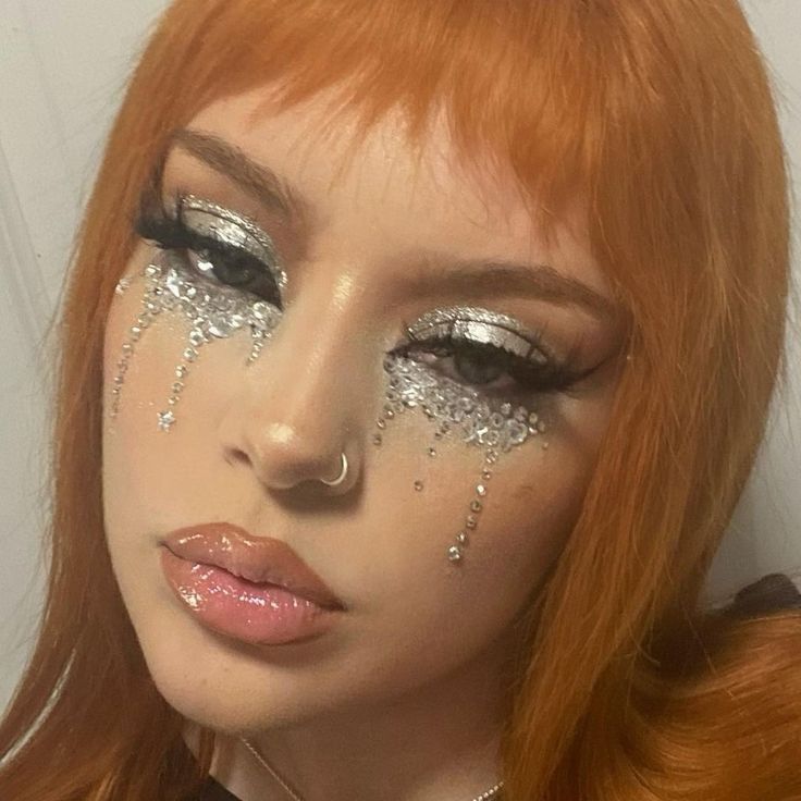 a woman with red hair and silver glitter make - up looks at the camera while posing for a photo