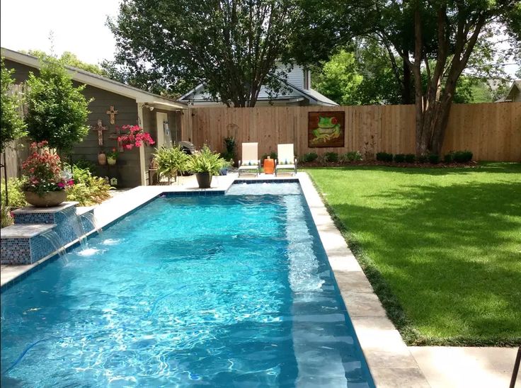 a backyard with a swimming pool surrounded by grass