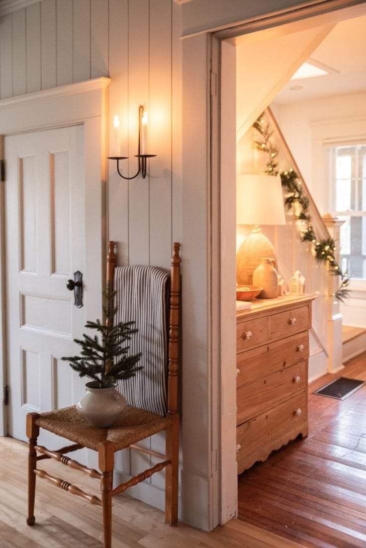 a chair sitting in front of a white door next to a christmas tree on top of a wooden table