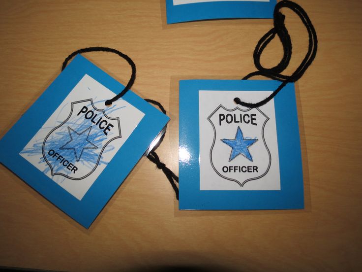 two police badges on a wooden table with black string attached to the tags that are blue and white