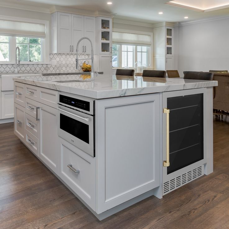 a large kitchen with an island in the middle and white cabinets on both sides is shown