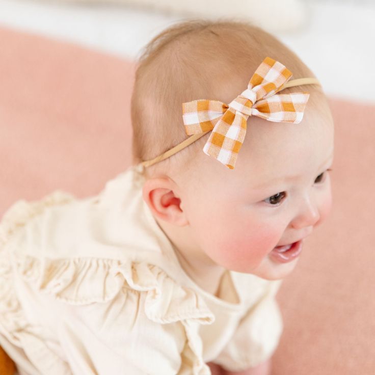 The Baby Bow on Nylon in Mustard Gingham This adorable hair bow is the perfect accessory for your babe! Baby Bows are 3" wide and attached to a comfortable nylon headband. Imported. Adjustable Bow With Matching Headband For Spring, White Headband For Spring Playtime, Cute Adjustable Bow For Summer, Playful White Bow With Matching Headband, Cute Adjustable Summer Bow, Playful Adjustable Bow With Matching Headband, Adjustable Playful Bow With Matching Headband, Adjustable Playful Bow For Summer, Playful Adjustable Bow For Summer