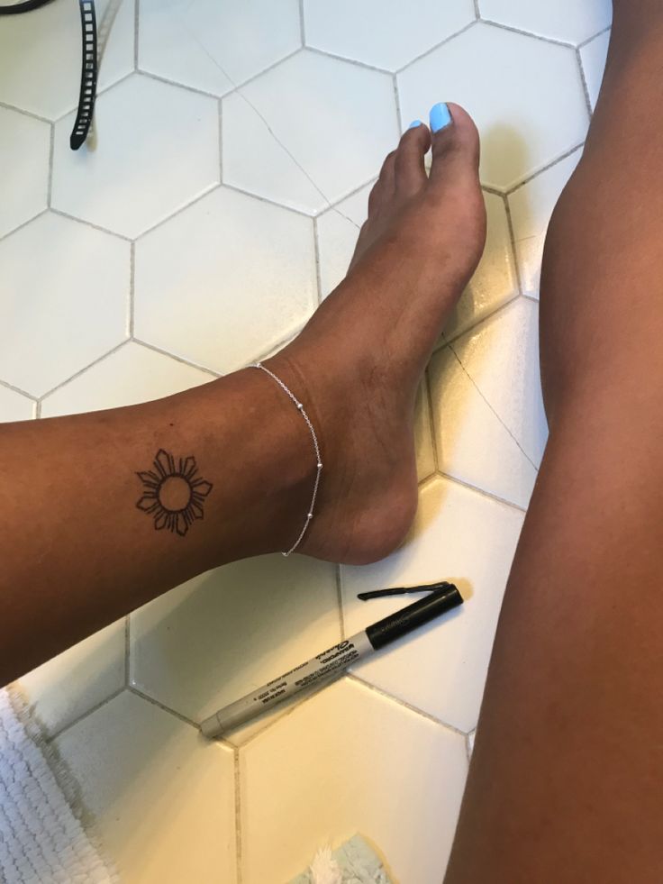 a person with a tattoo on their leg sitting on the floor next to a pen