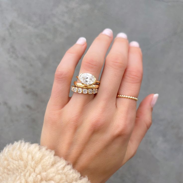 a woman's hand with two rings on her fingers and one ring in the middle