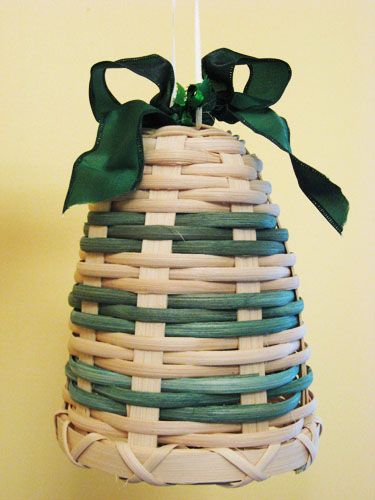 a basket hanging from a wall with a green bow on it's top and bottom