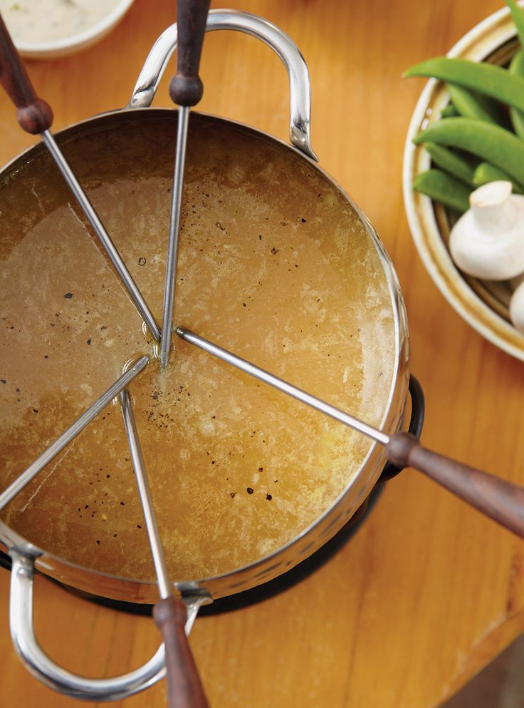 a pot with some food inside of it on a table next to bowls and spoons