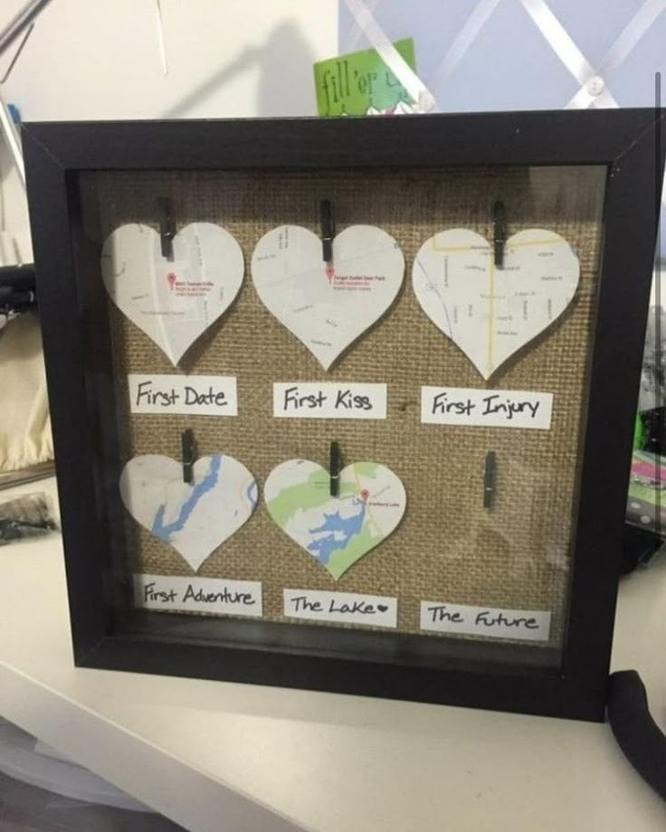 there are many hearts in the frame on the desk with labels attached to them that say first kiss, first injury, first love