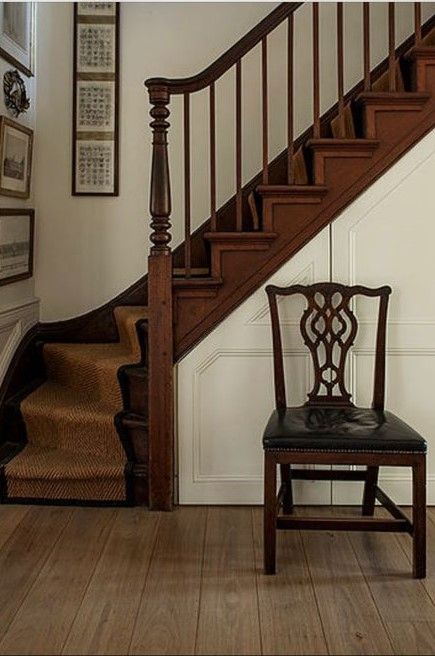 a chair sitting in front of a stair case next to a wooden bannister