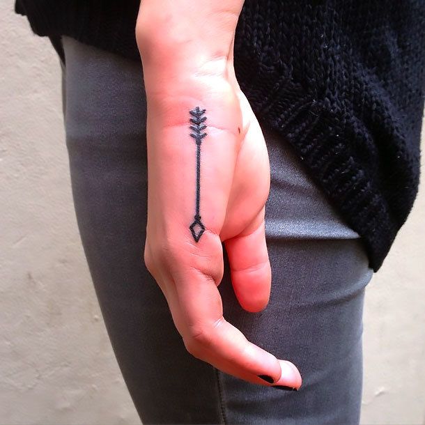 a woman's hand with a small arrow tattoo on it