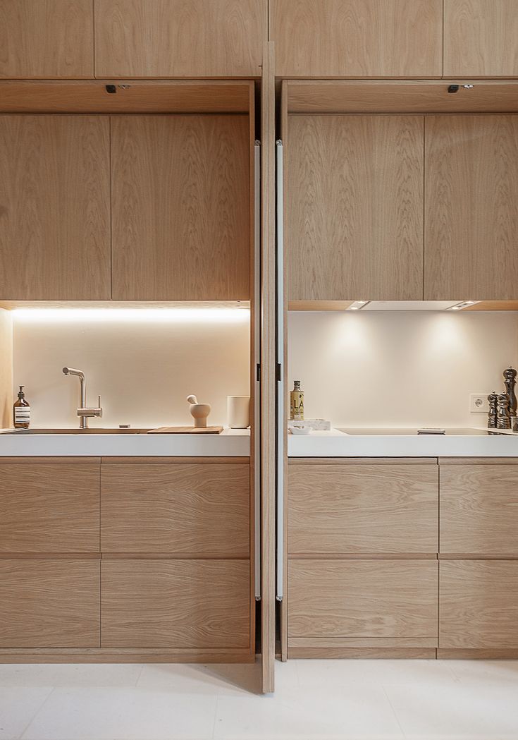 two wooden cabinets with white counter tops and lights on the top one is open to let light in