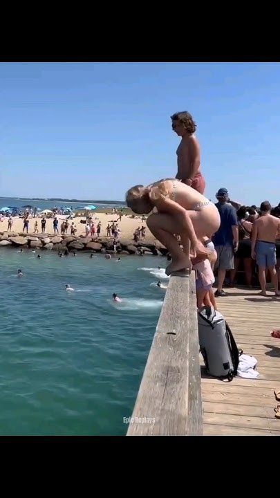 people are standing on a pier near the water and swimming in the blue ocean while others watch