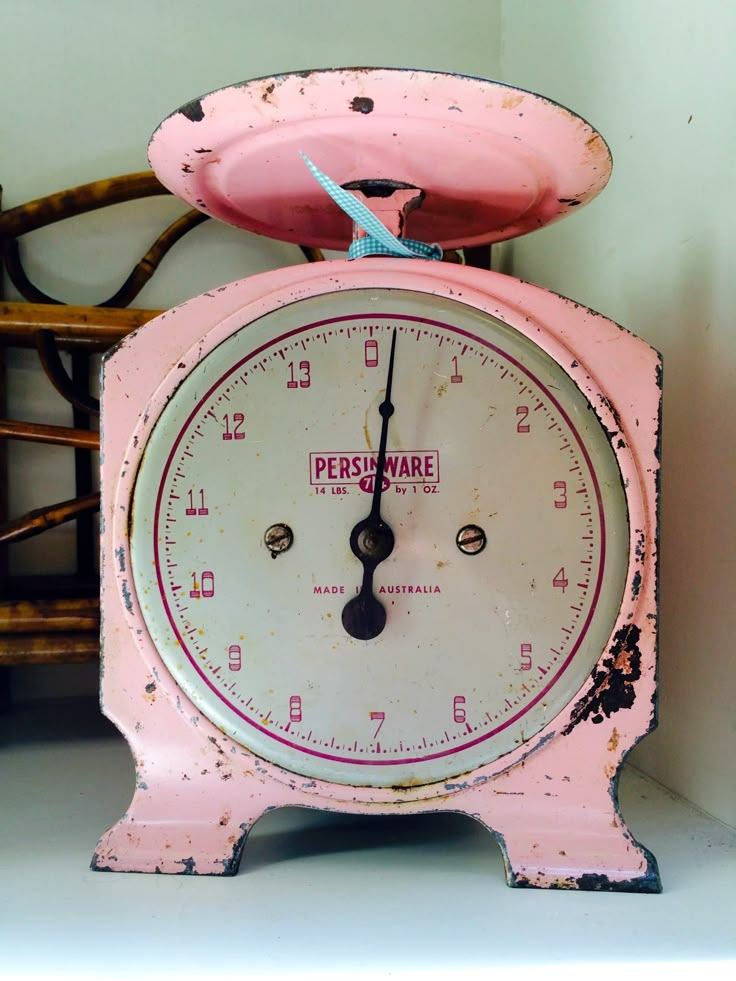 an old pink clock sitting on top of a chair