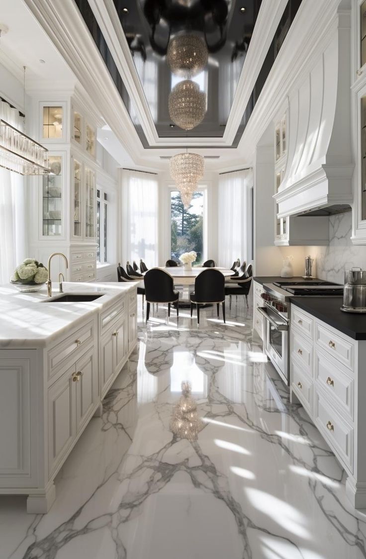 a large kitchen with white cabinets and marble flooring is pictured in this image, there are chandeliers hanging from the ceiling