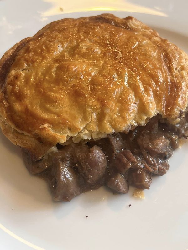 a piece of meat pie sitting on top of a white plate