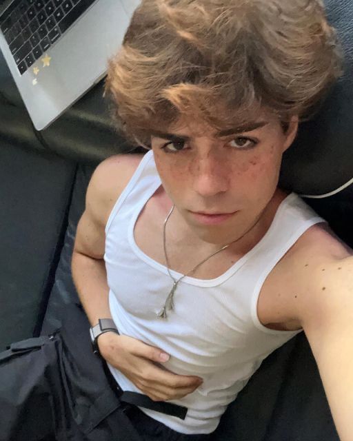 a young man laying on top of a bed next to a laptop computer