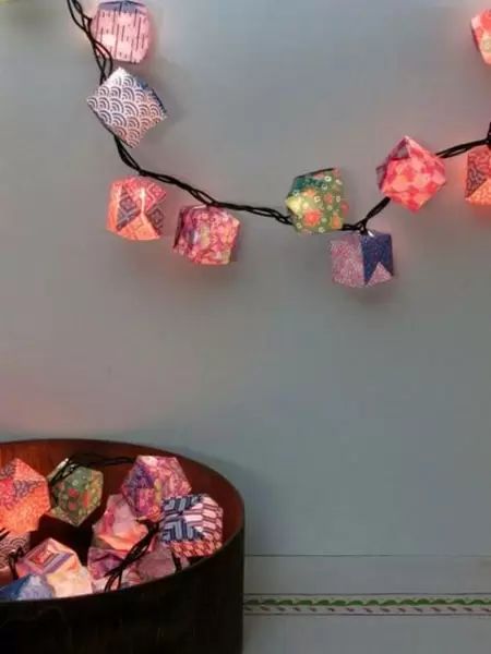 a string of paper cubes is hanging from the wall next to a basket full of candy