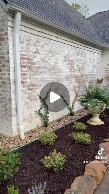 a brick house with landscaping in front of it and a small garden area on the side