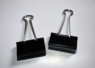 pair of black binders on white surface with clippings attached to each end