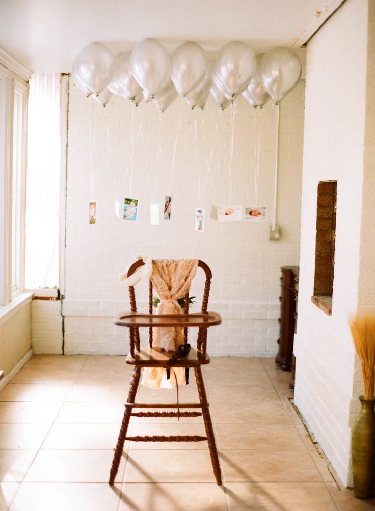 a baby's highchair with balloons hanging from the ceiling in an empty room