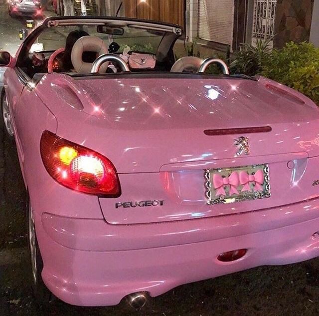 a pink convertible car parked in front of a building