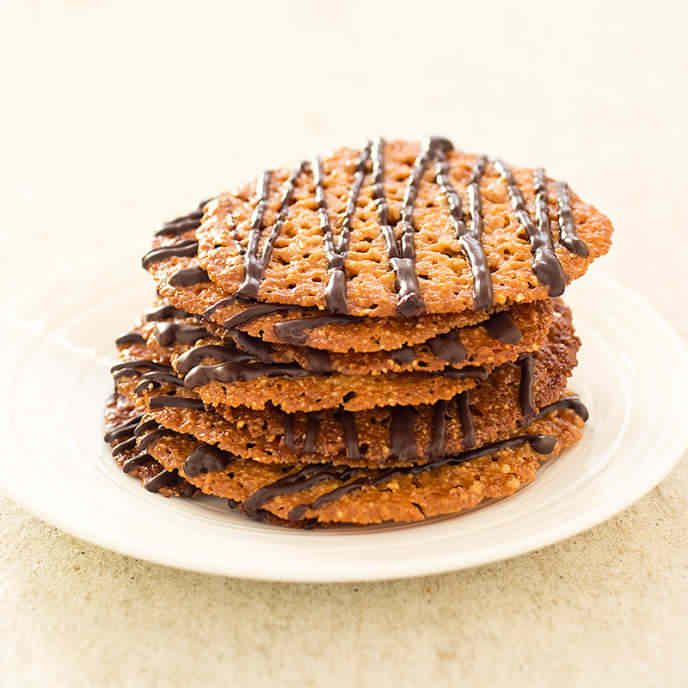 a stack of cookies with chocolate drizzled on top sitting on a white plate