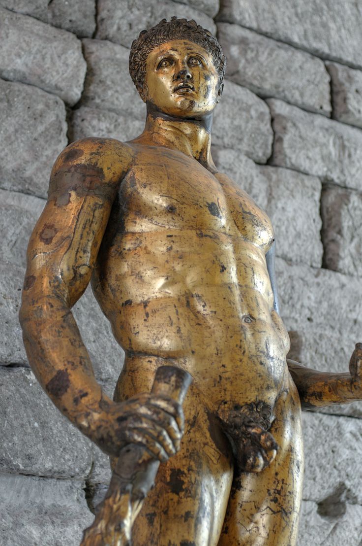 a statue of a man holding a baseball bat in front of a stone wall with bricks on it