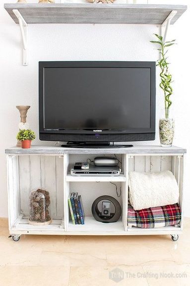 a flat screen tv sitting on top of a white entertainment center next to a potted plant