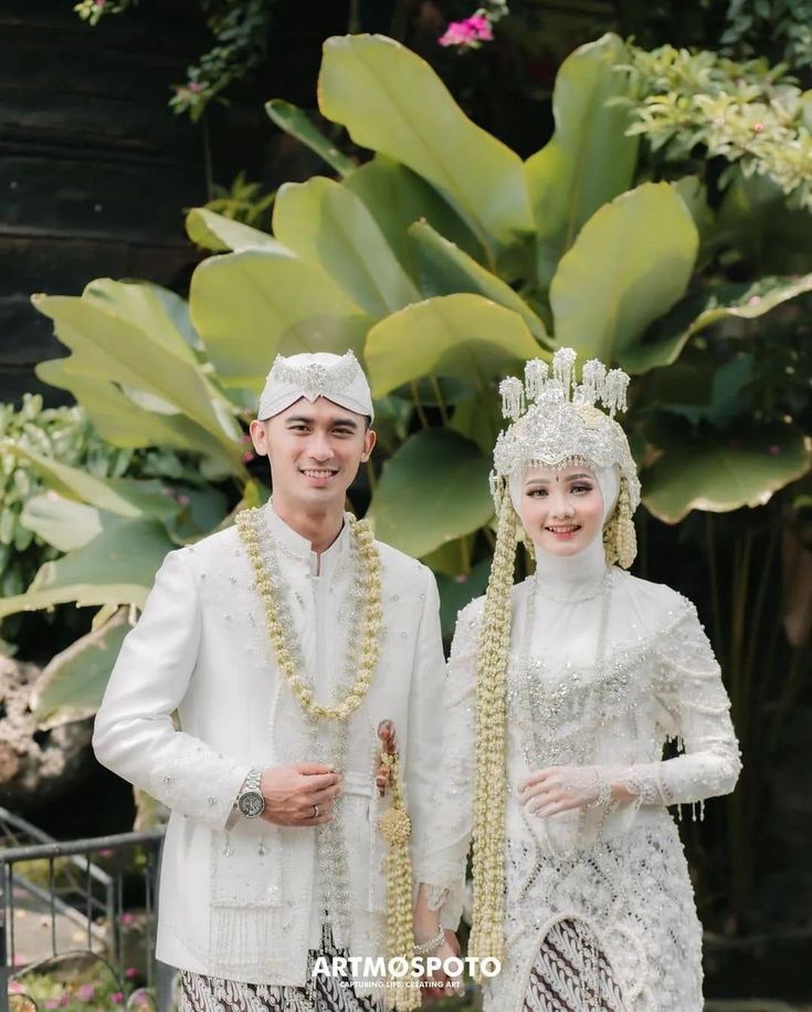 two people dressed in white standing next to each other