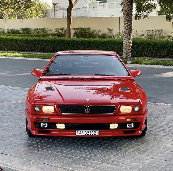 a red sports car parked in front of a palm tree