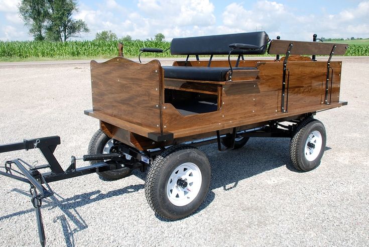 an old wooden wagon with two seats on the back is parked in a parking lot