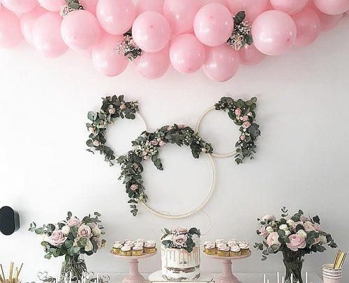 a table topped with cakes and cupcakes covered in pink balloons