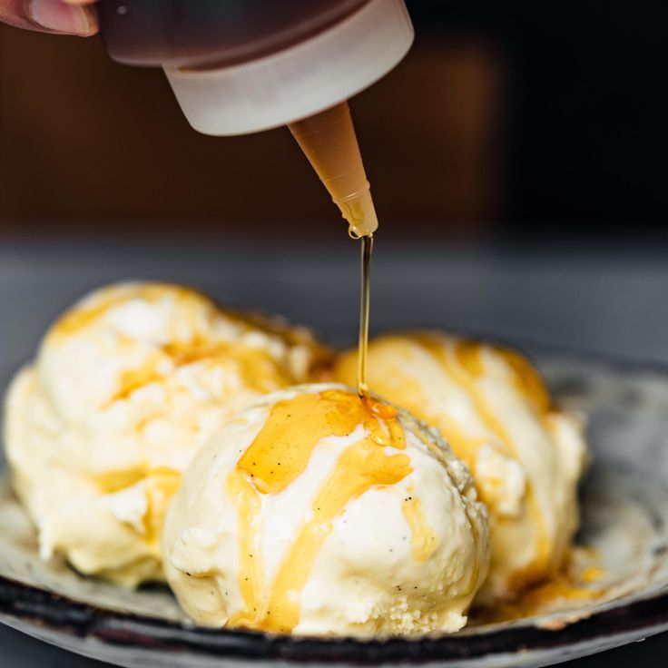 an ice cream sundae is being drizzled with caramel syrup