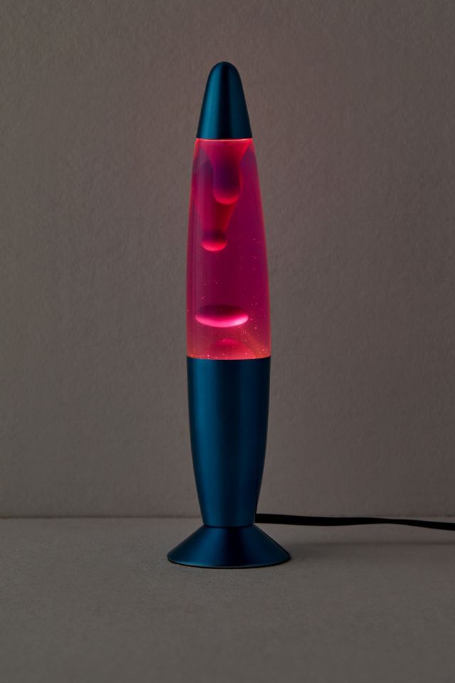 a blue and pink lamp sitting on top of a table next to a gray wall