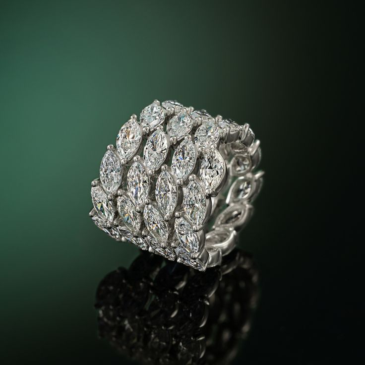 a diamond ring sitting on top of a black table next to a green background with reflection