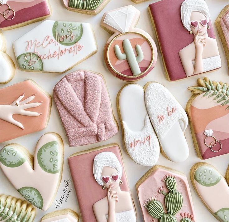 many decorated cookies are arranged on a white surface with pink, green and gold accents